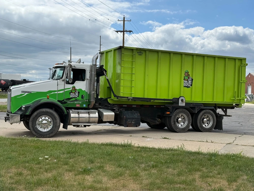 Roll off truck hauling a dumpster rental container showing how to pick a larger size for heavy debris loads and demolition.